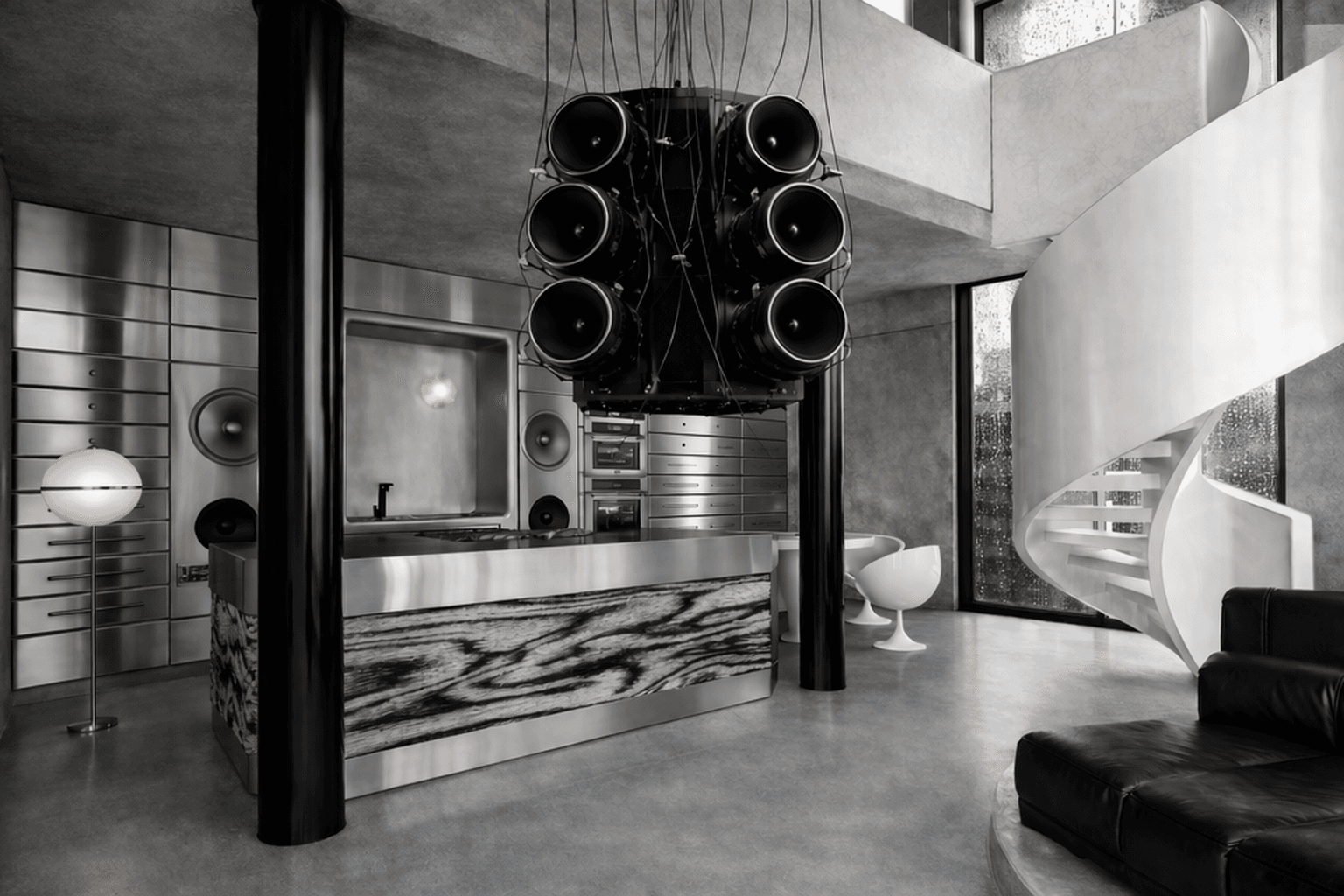 Stainless steel kitchen with black column and white sculptural seating.